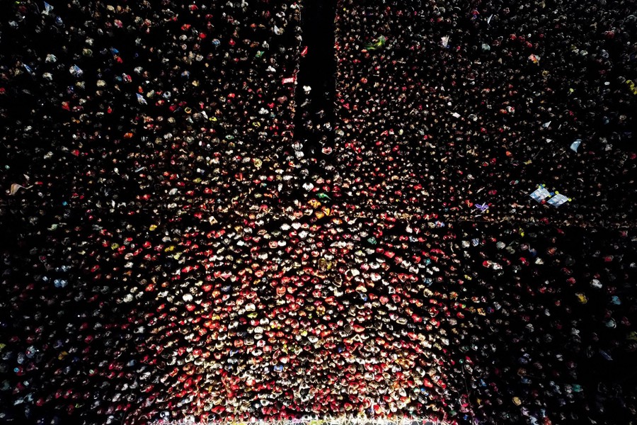 An aerial view of a crowd of supporters tightly packed against a stage