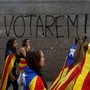 Students wear Esteladas (Catalan separatist flag) during a demonstration in front of a graffiti on the wall that reads, "We will vote!"