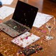 Confetti is strewn across a laptop, notebook, and wine glass