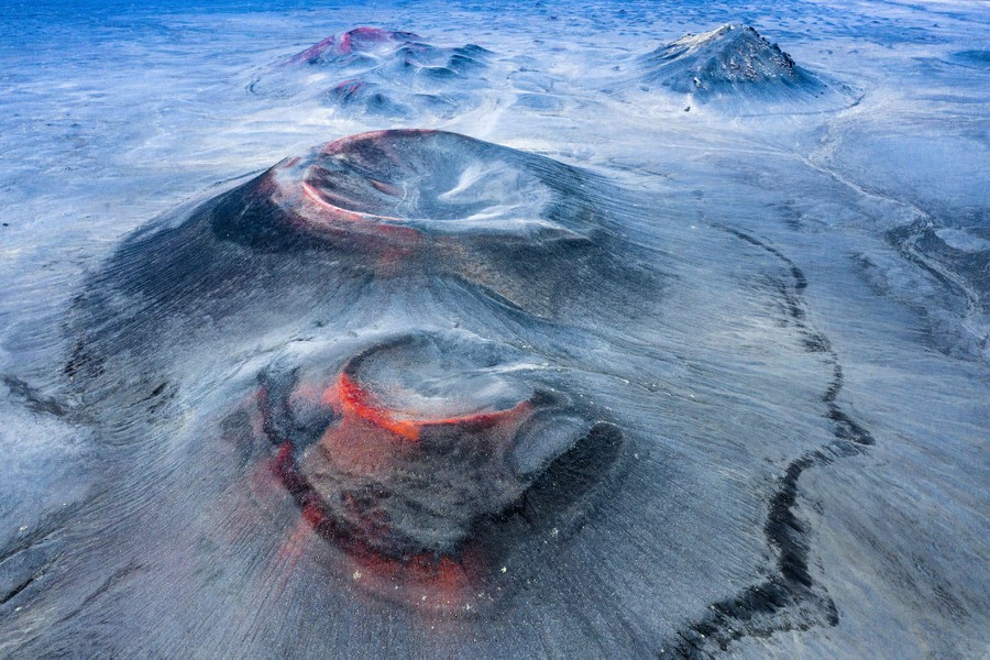 Low, rounded volcanoes are seen on a treeless landscape, from above.