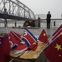 Chinese vendors sell North Korea and China flags on the boardwalk next to a bridge that connects China and North Korea.