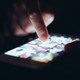 A finger touches an illuminated phone screen