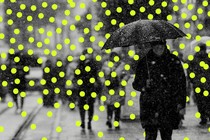 Photo of someone, masked, on the street with an umbrella; glowing dots overlaid like snow