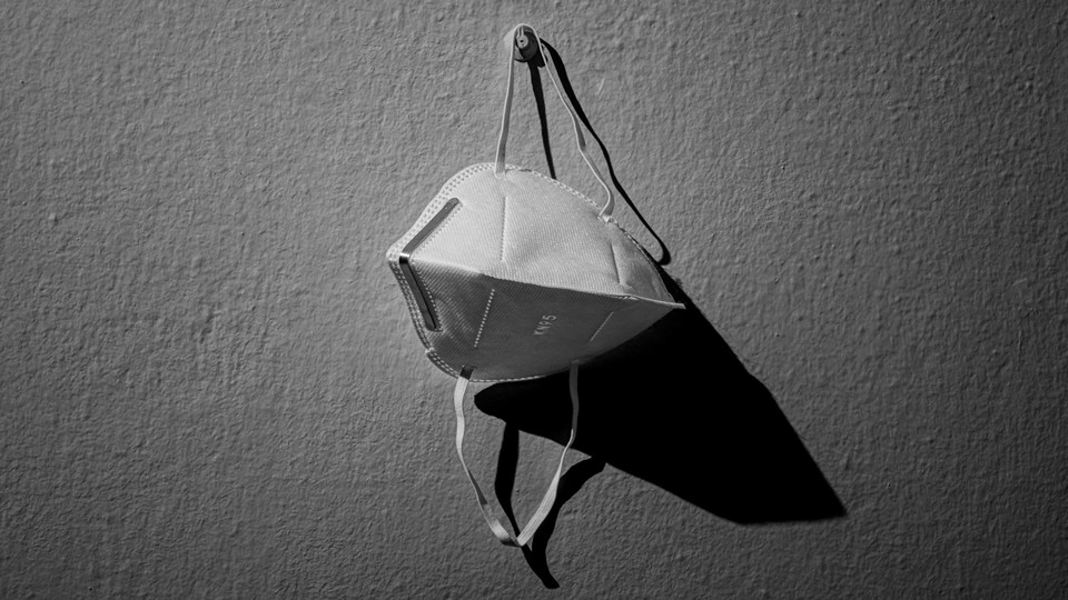 An image of a kn95 mask hanging on a hook against a white wall