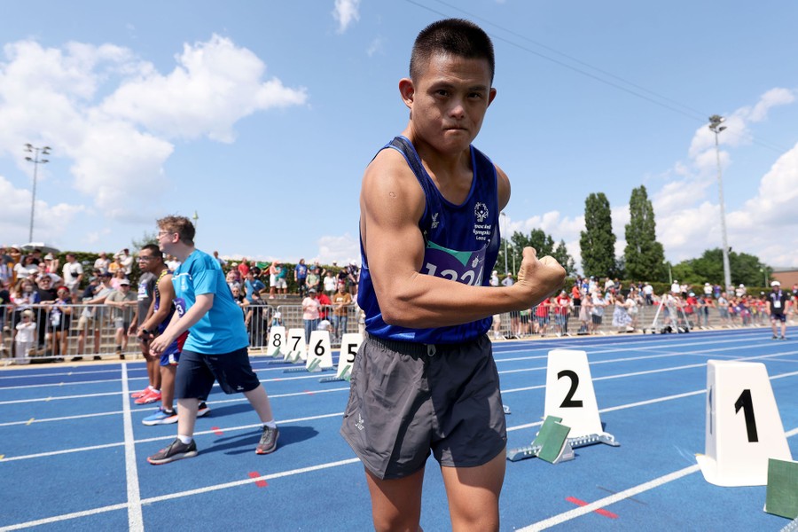 A track and field athlete poses, showing off a muscular arm, before a race.