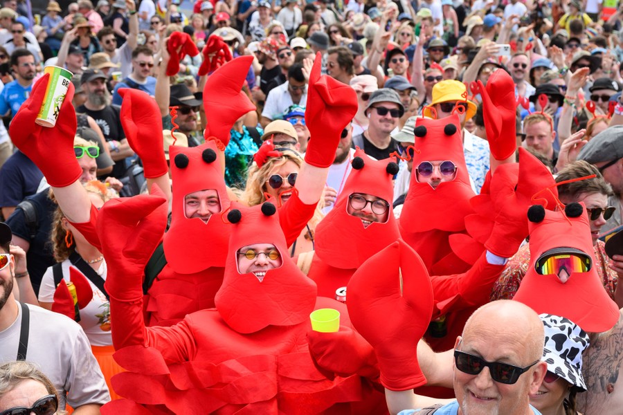 A half dozen fans among a larger crowd pose while wearing lobster costumes.