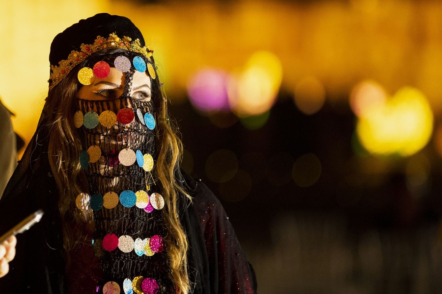 A person in a traditional costume with a colorful veil prepares to perform.