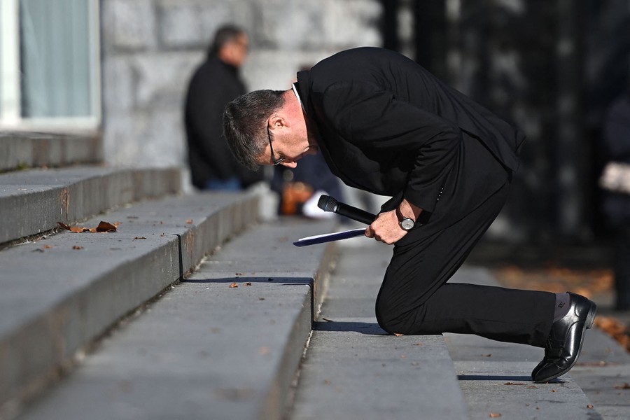 A man kneels down on steps outside a church.