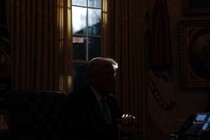 An image of Donald Trump sitting next to a window