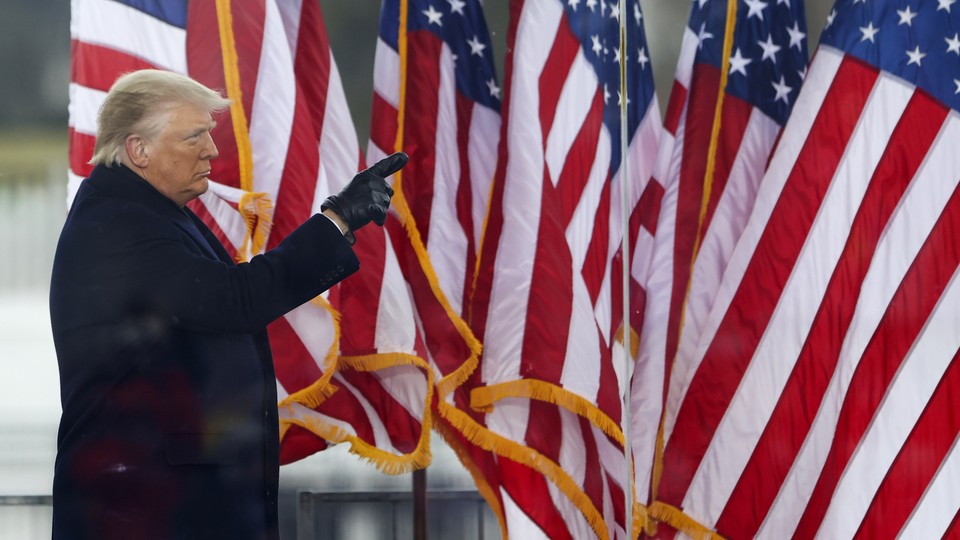 Donald Trump pointing, standing in front of American flags