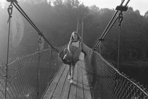 A girl carrying a sleeping bag walking over bridge