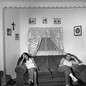 black-and-white photo of two women sitting at opposite ends of sofa in living room