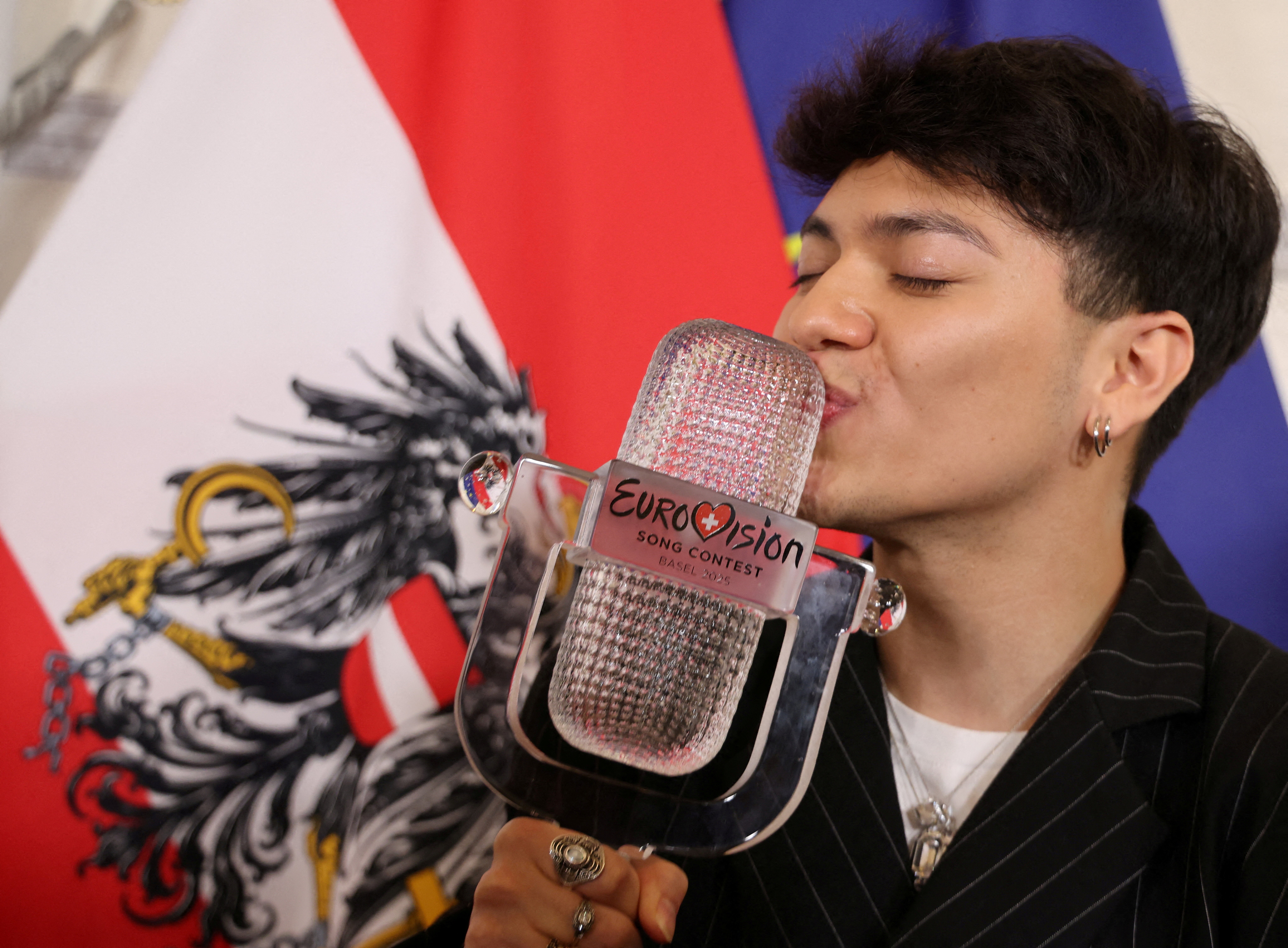 The performer kisses a trophy made of glass, shaped like a large microphone.