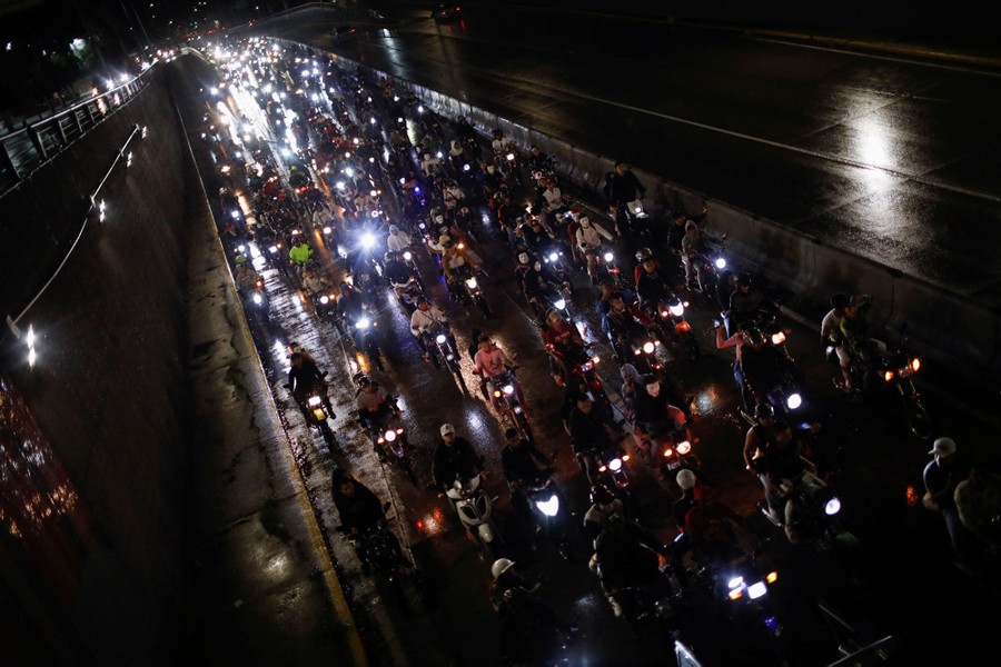 People in costumes ride motorcycles in a large group on a city street.