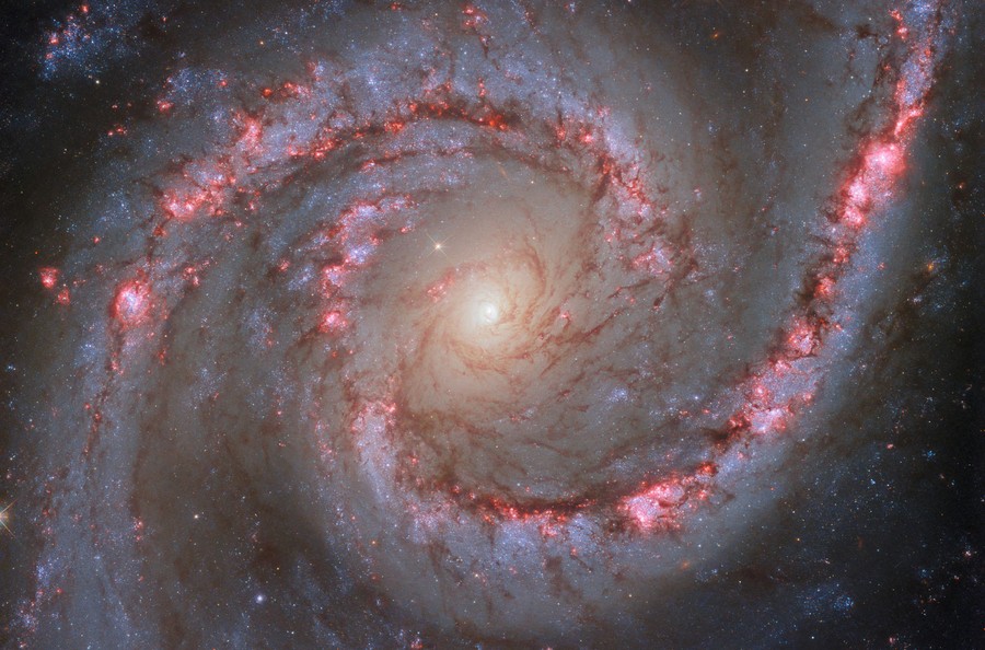 A view of a spiral galaxy, featuring two prominent arms lined with dark and light patches, and a bright center