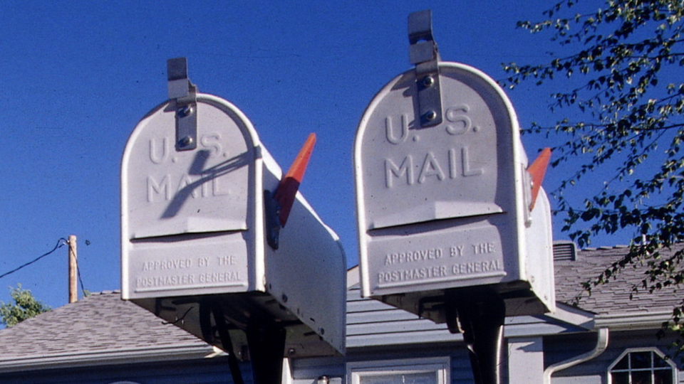 A color photograph of two gray metal mailboxes with their signaling flags up