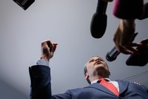 A photo shows Pete Hegseth surrounded by microphones