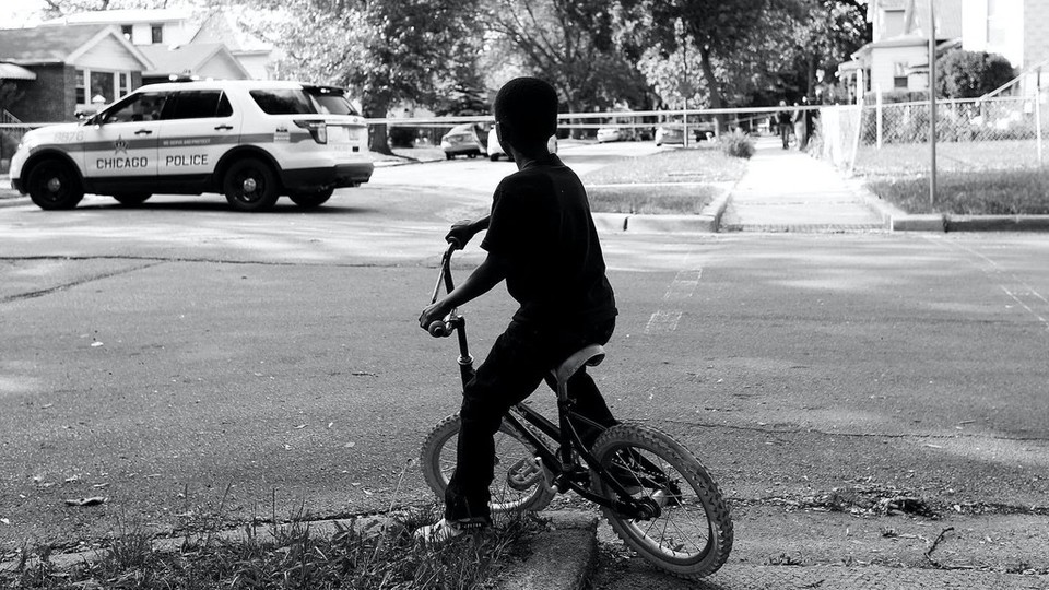 Child on a bike with a police car in the background.