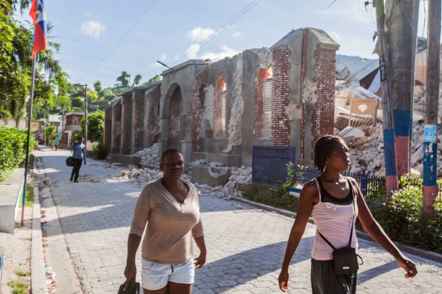 People walk beside a collapsed church.