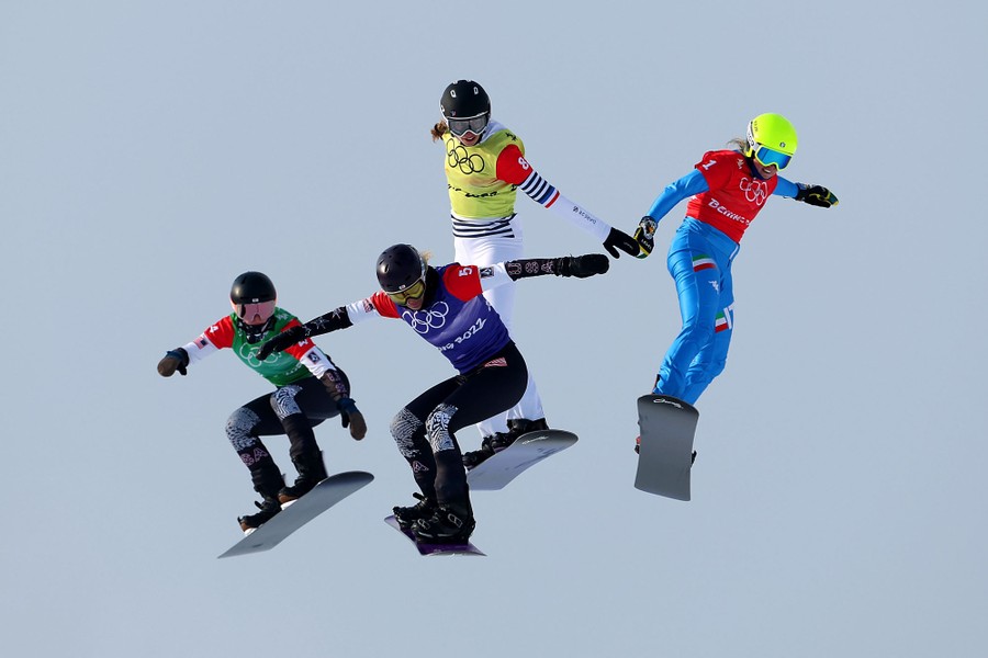 Four snowboarders are seen in mid-air during a snowboard cross run.
