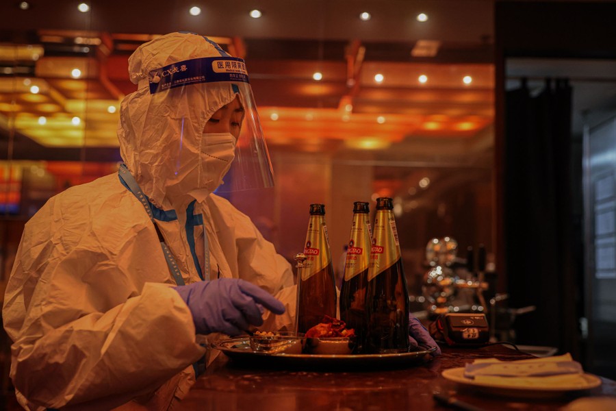 A restaurant worker readies a tray while wearing a full-body hazmat suit.