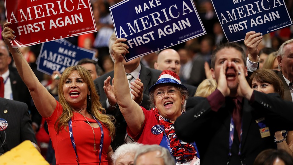 Delegates hold up signs that read "Make America First Again" during the opening of the third day of the Republican National Convention on July 20, 2016.