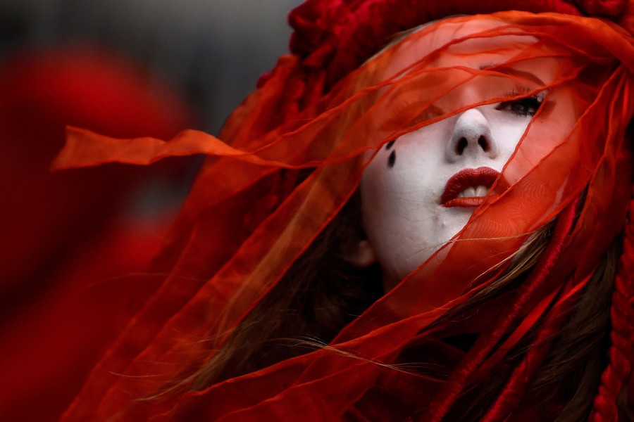 A portrait of a person wearing red with ribbons over their face.