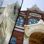The Smithsonian Institution Arts and Industries Building is reflected in a sign displaying an antique drawing of the building