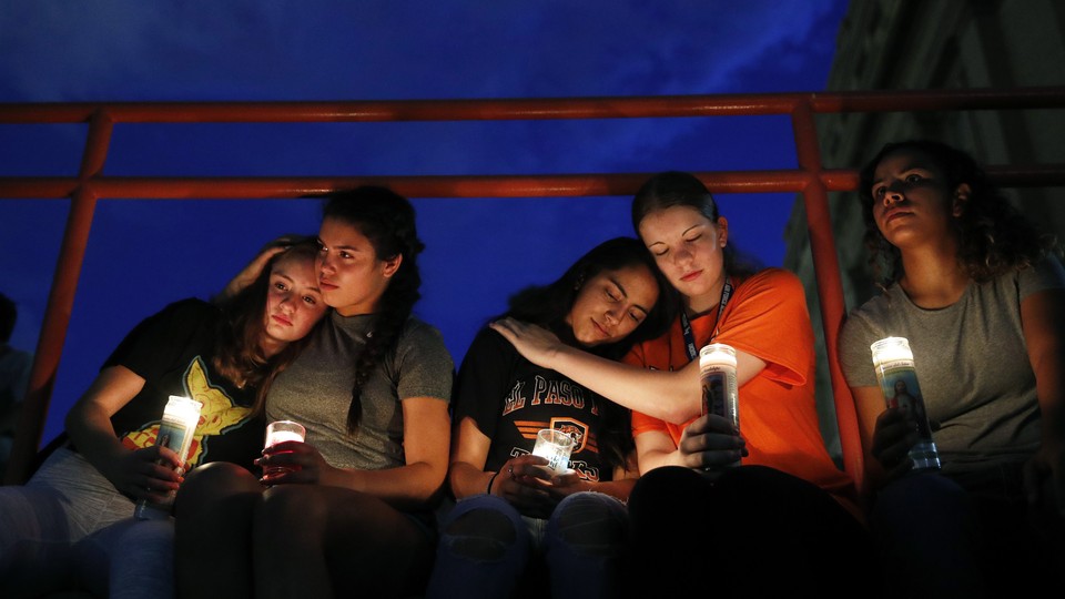 Young women comfort each other at a vigil in El Paso.