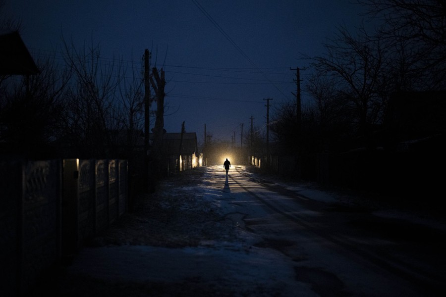 A man is silhouetted in the headlights of a car during a blackout.