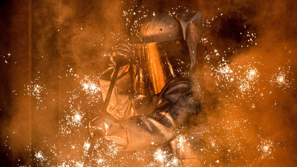 A worker in a protective suit oversees molten iron flowing from a blast furnace at the ThyssenKrupp steel mill in Duisburg, Germany.