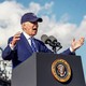 A photo of President Biden giving a speech while wearing a cap