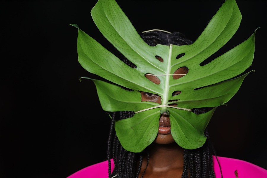 A model wears a mask made from a large leaf.