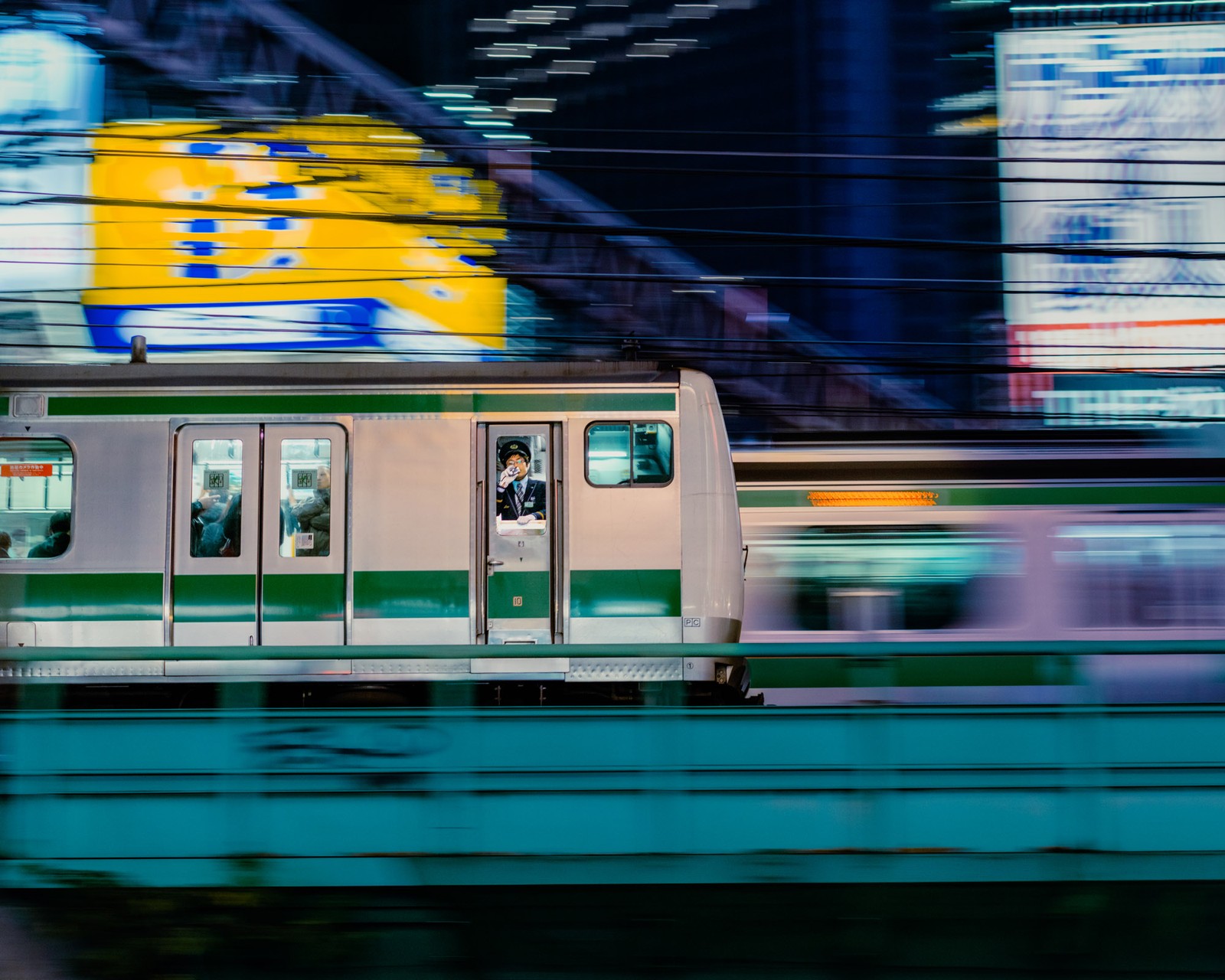 A train rushes past, the background blurred with motion, and a conductor visible inside the train.