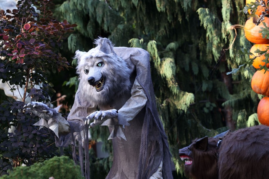 A pair of werewolf statues stand outside a house.