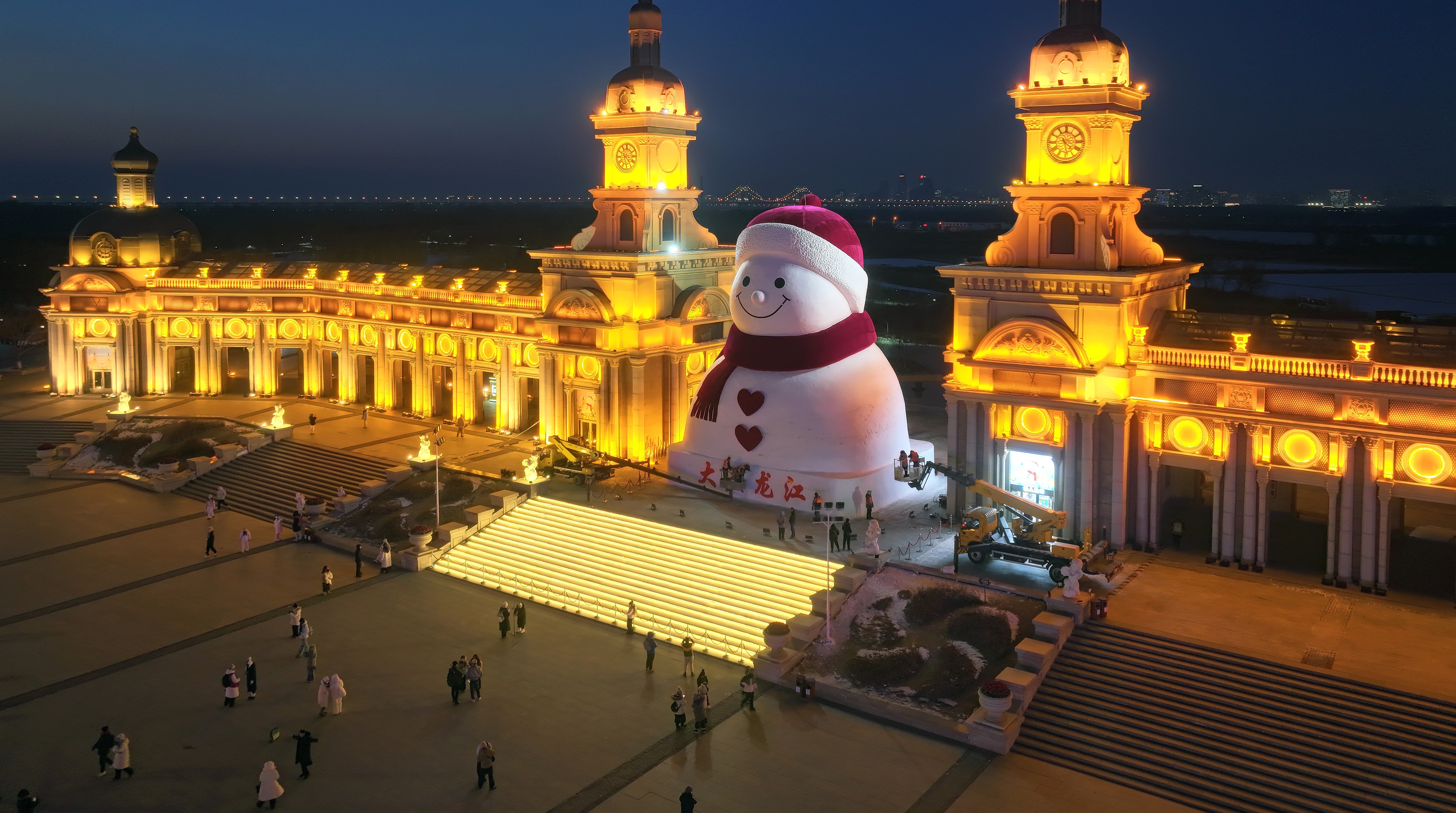 A giant snowman sculpture stands at the gate to a park.