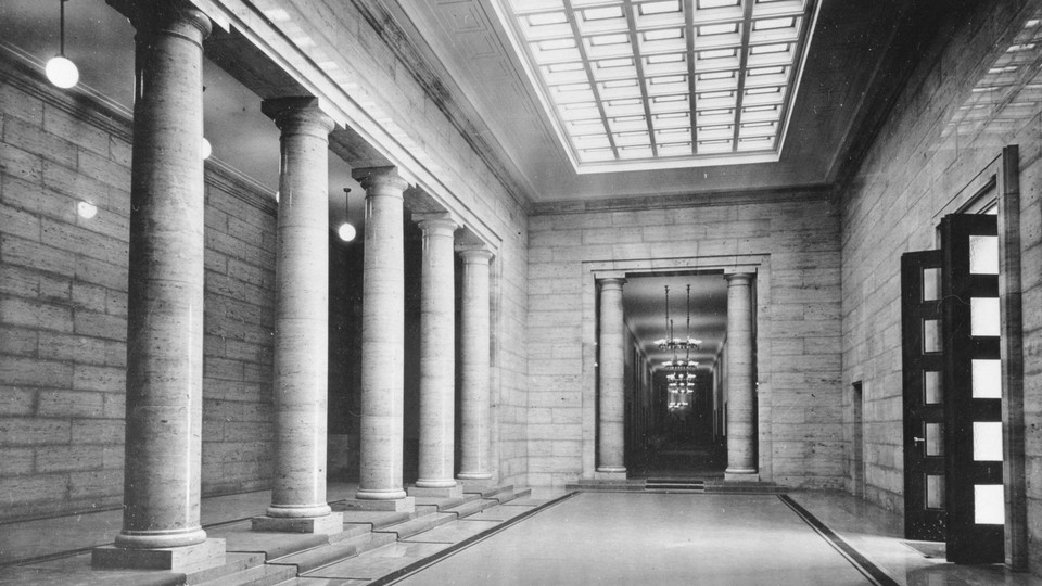 Columns lining a long marble hallway with skylights and chandeliers