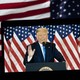 A TV image of former President Donald Trump speaking in front of U.S. flags