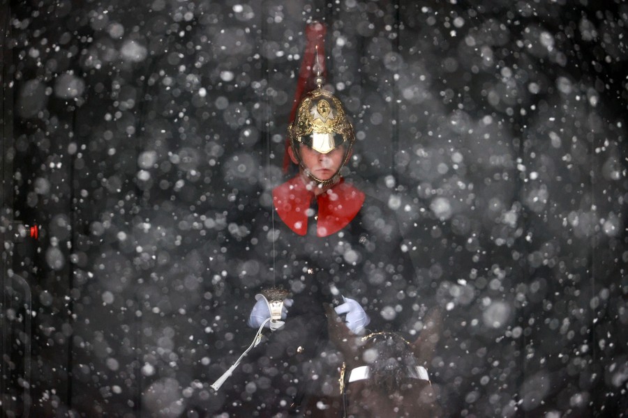A soldier on horseback is viewed in a snowstorm.