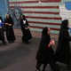 Iranian students walk past an anti-American mural, the Statue of Liberty with skull head and Iran's map.