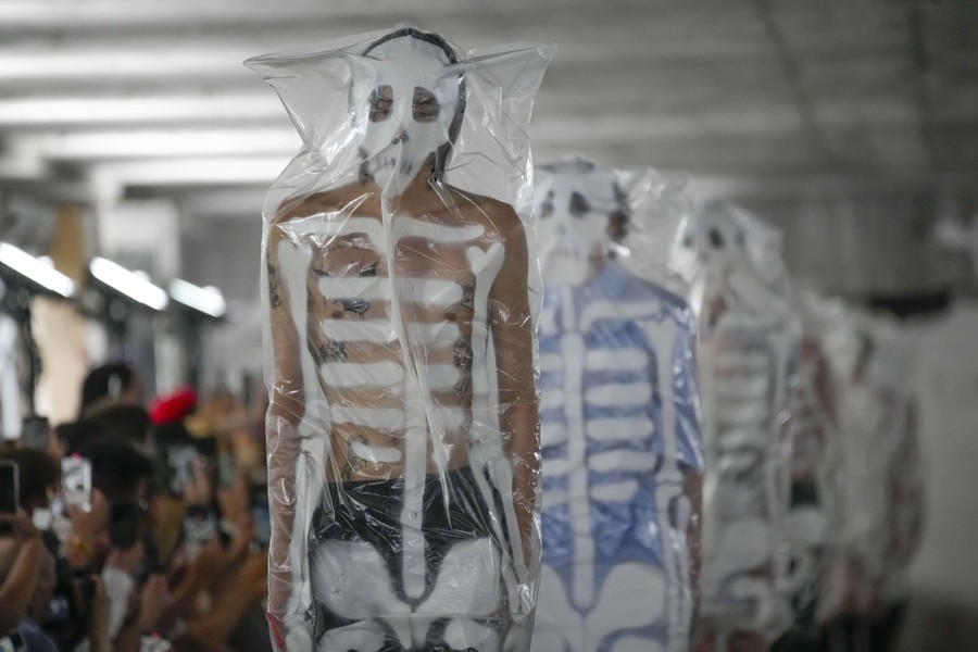 fashion models wear clear plastic garments painted roughly as skeletons.