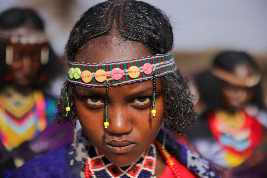 A woman dressed in traditional clothing looks toward the photographer.
