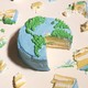 A cake decorated to look like earth from above with a large slice taken out and pieces scattered.