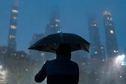 A person holds an umbrella in the wet and snowy city