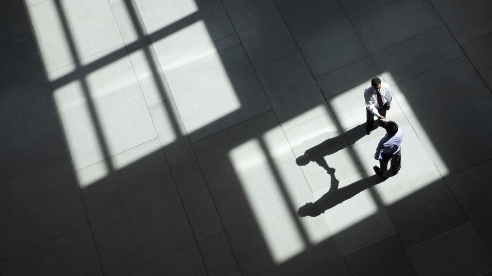 Two businessmen shake hands in a lobby