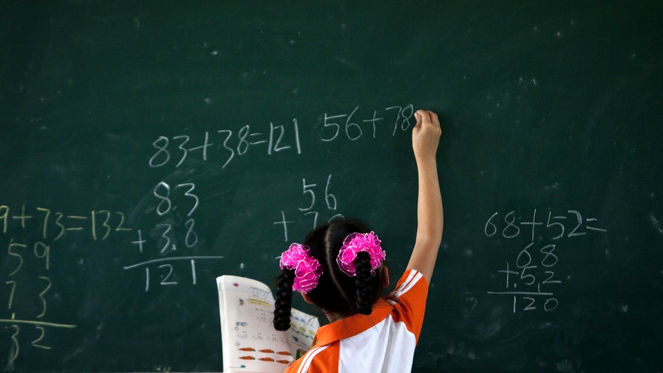 A girl wearing pigtails does math problems on a chalkboard 