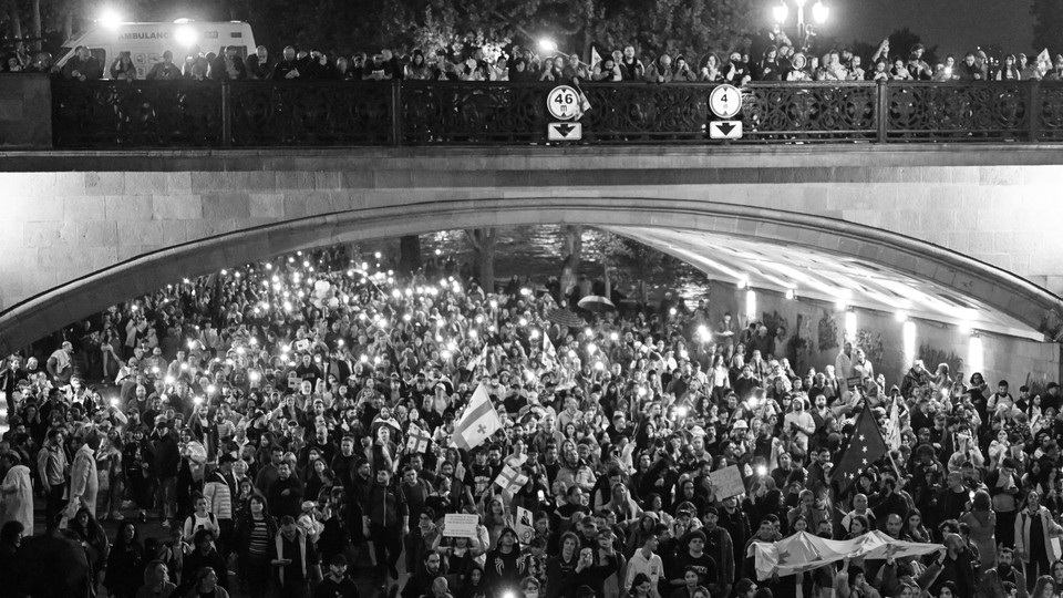 A black-and-white photo of protesters crowded under and on top of a bridge in Georgia.