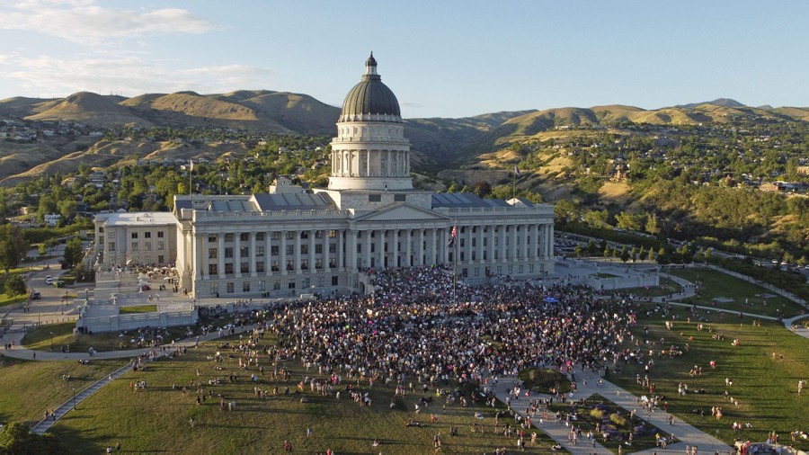 A large crowd of protesters gathers in front of a state capitol building.