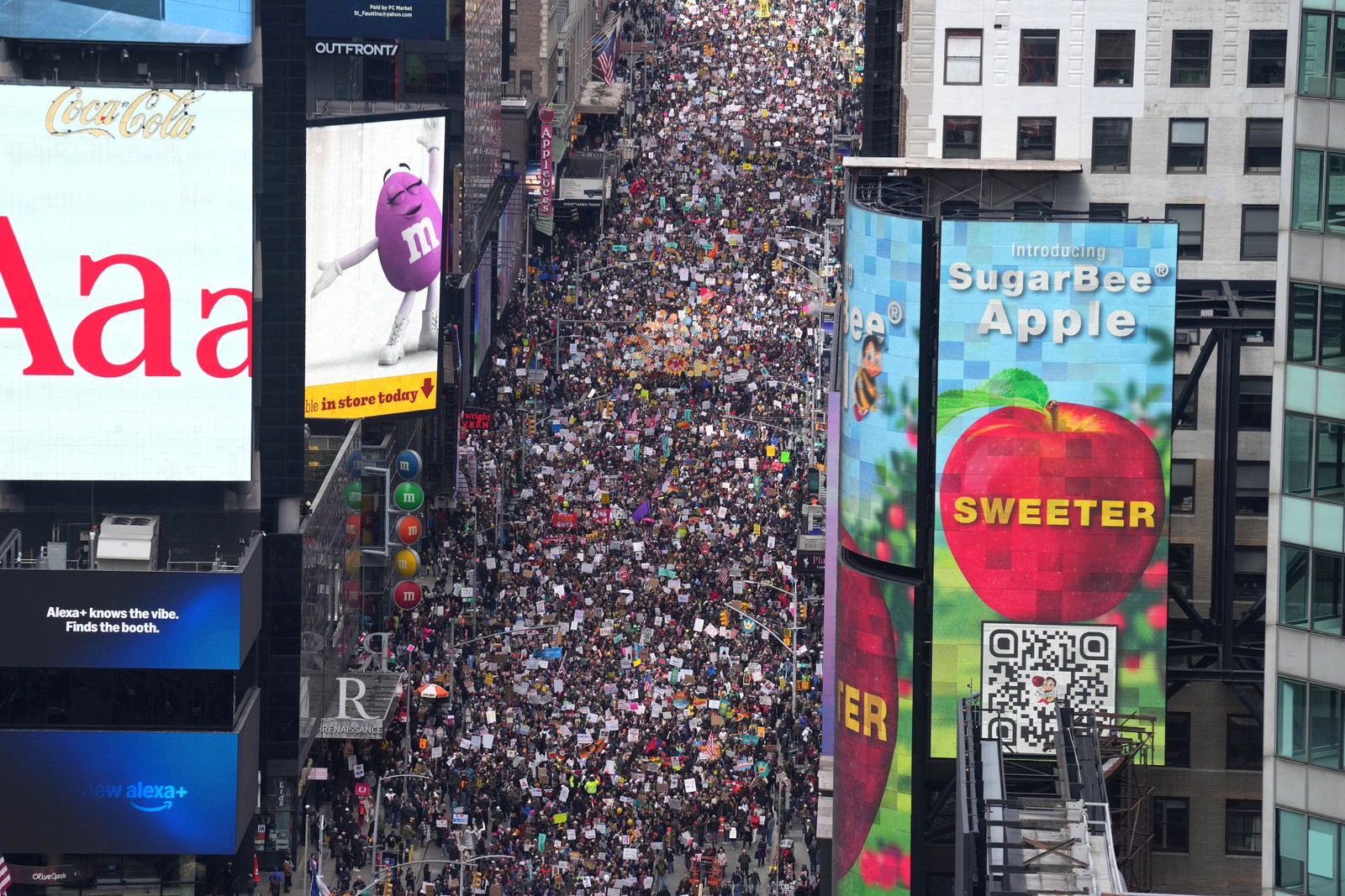 An elevated view of thousands of people marching together in a protest in a New York City street.