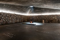 A gray floor inscribed with names surrounded by a stone wall with a pyramidal roof